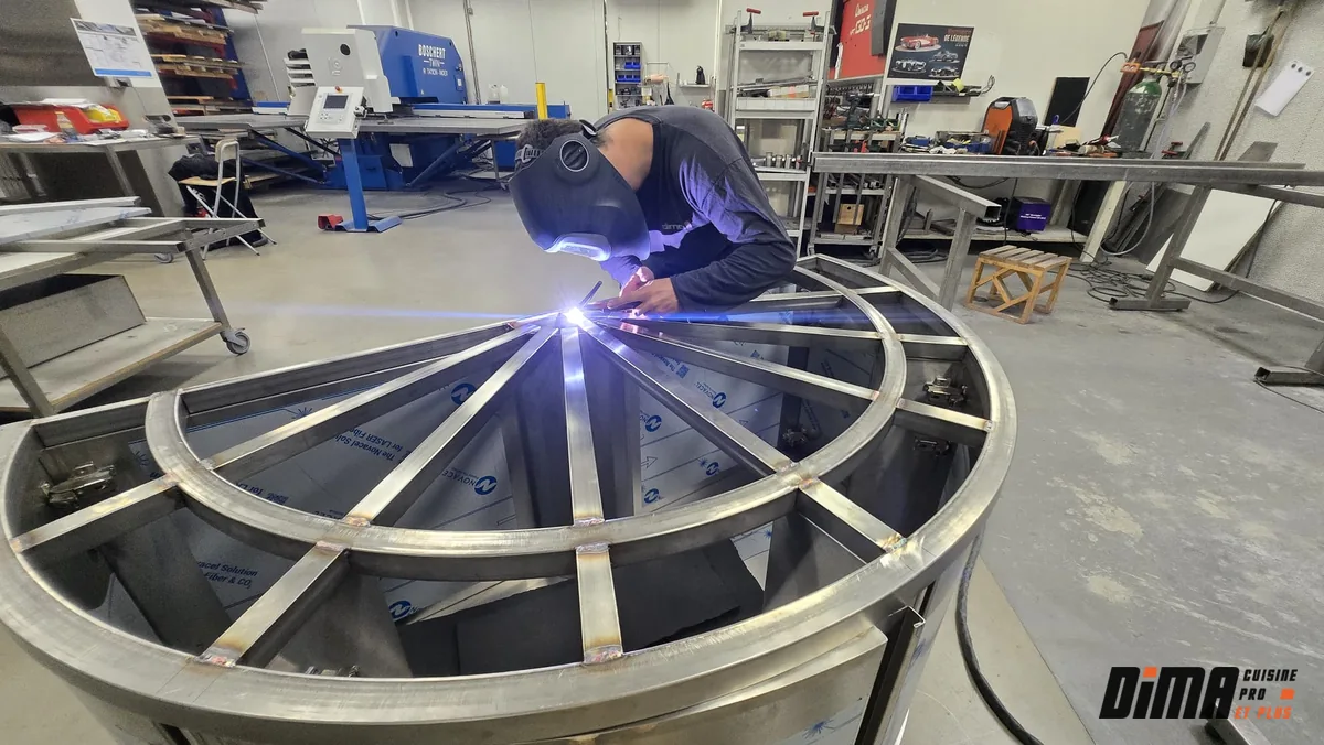 Vue d'ensemble d'un atelier : un technicien fait de la soudure sur inox.